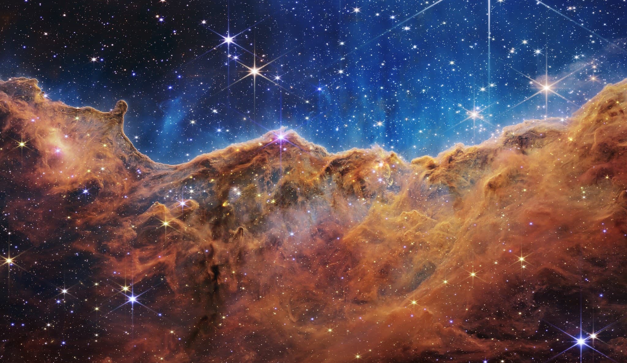 The Cosmic Cliffs of NGC 3324, a ridge of gas and dust glowing against young stars.